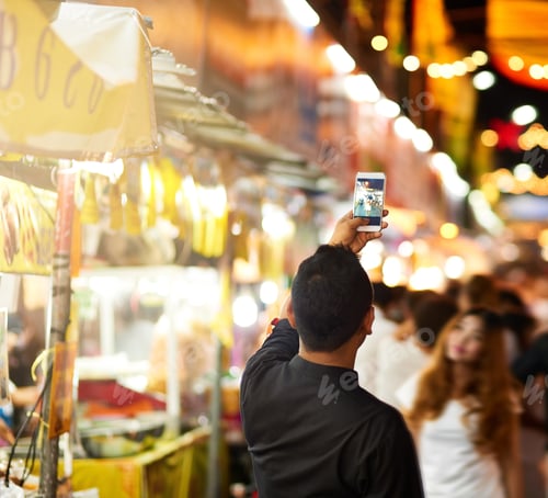 Preview: Rearview shot of a young man taking pictures while touring a foreign city