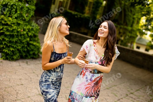 Preview: Pretty young women walking and eating ice cream by the old house with ivy