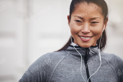 Preview: Smiling Asian woman in sportswear standing alone outdoors before exercising