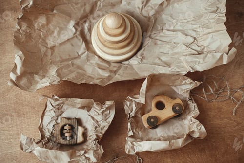 Preview: Stylish wooden toys for child on paper on wooden table, flat lay. Eco friendly plastic free toys