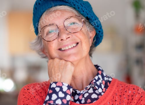 Preview: Closeup portrait of beautiful smiling senior Caucasian woman looking at camera. Blue cap and glasses