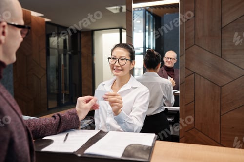 Preview: Happy young businesswoman taking card from hotel room after filling in form