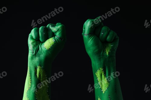 Preview: Green hands clenched into fists on black background, close up