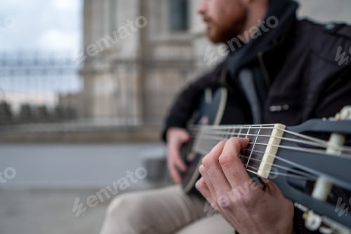 Preview: Close-up of a man's hands playing guitar sitting on the street. Music concept