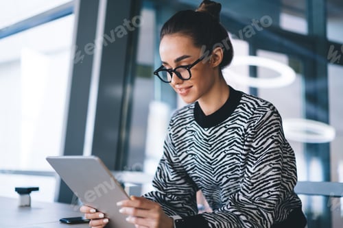 Preview: Focused positive young woman using tablet in office