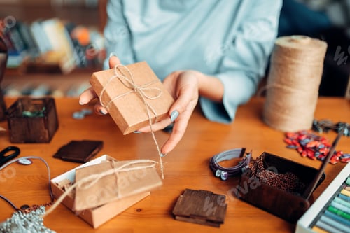 Preview: Female person tie a bow on a gift box, needlework