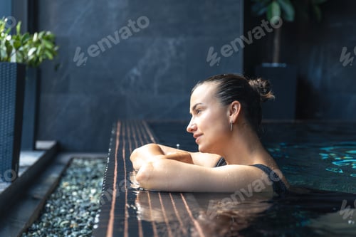 Preview: Woman leaning on pool edge with dreamy look. Calm pause.