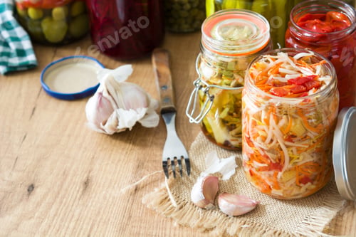Preview: Preserved vegetables in glass jars with garlic on rustic wooden table