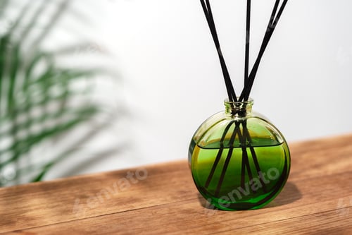 Preview: Green Glass Reed Diffuser On Wooden Tabletop With Greenery In Background