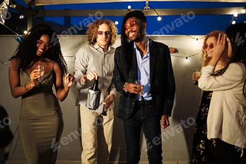 Vorschau: Multiethnische Freunde genießen eine Dachparty mit Getränken und Wunderkerzen