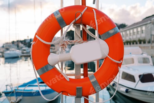 Preview: Red lifebuoy on a holder hanging from a pole on the pier