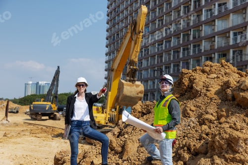 Preview: Two construction professionals, one holding blueprints and the other using a walkie-talkie