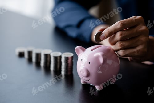 Preview: A businessman holding a coin in a piggy bank.