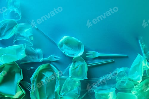 Preview: top view of crumpled plastic cups, straws and forks with copy space in blue light