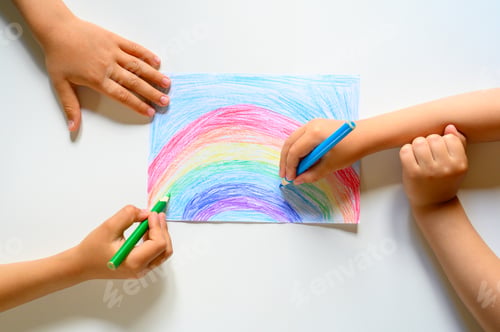 Preview: kid's hands together draw a rainbow colored pencils on white background