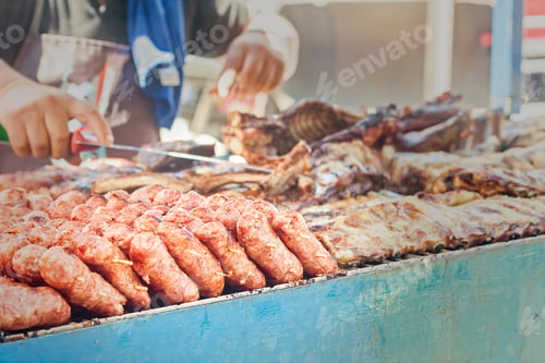 Preview: Sausages on the grill. Blurred in the background the Cook and other meats to cook.