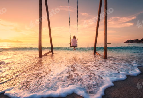 Preview: Happy young woman on wooden swing in water, sea with waves