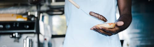 Preview: panoramic shot of afrian american man holding spatula while preparing burger