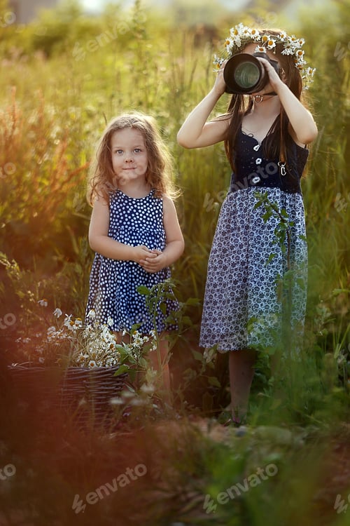 Preview: two girls in the meadow, one is looking at the other in the camera