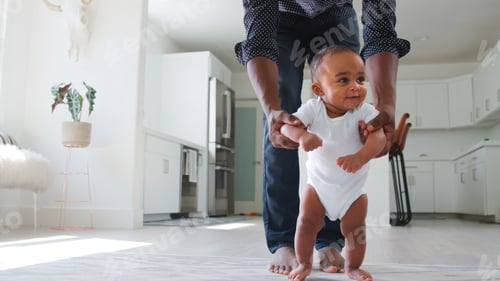 Preview: Close Up Of Father Encouraging Smiling Baby Daughter To Take First Steps And Walk At Home