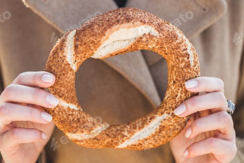 Preview: Beautiful woman holds a traditional Turkish simit in hands and wants to eat it