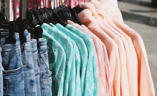 Preview: clothes rack with pastel-colored spring fashion hanging outside store
