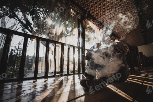 Preview: vaping young man produces vapor on sunset silhouette