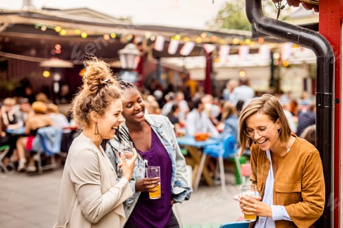 Preview: Young female friends relaxing in beer garden