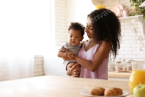 Preview: African-American woman with her baby in kitchen. Happiness of motherhood