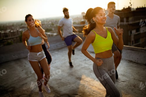 Preview: Group of young happy people friends exercising outdoors at sunset
