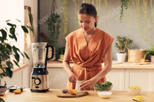 Preview: Young woman preparing ingredients for homemade smoothie