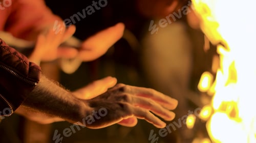 Preview: Close up of man warming up his hands at camp fire