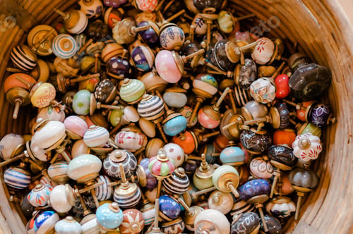 Preview: Top view of assorted and colorful vintage doorknobs in a wooden basin