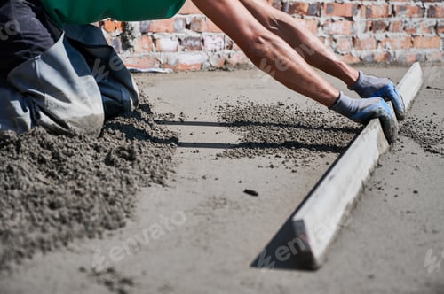 Preview: Male builder screeding floor at construction site.