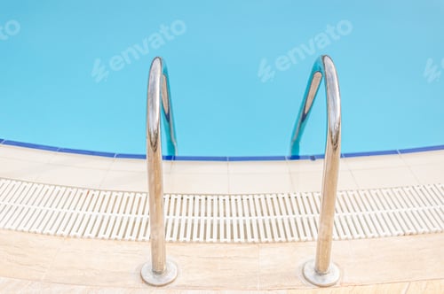 Preview: A pair of metallic lader handrail at the edge of swimming pool.