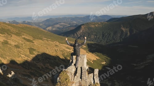 Preview: Traveler climb on mountain rock top aerial. Sun nature landscape. Man rising up and waving hands