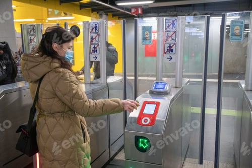 Preview: a young woman in a mask goes through the loket to the metro station and pays for the fare