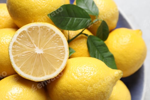 Preview: Fresh lemons and green leaves on table, closeup