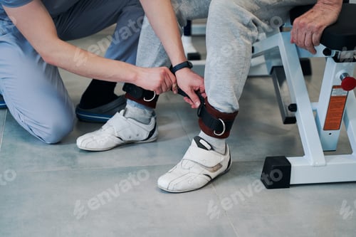 Preview: Medical person fastening strap on patient left ankle