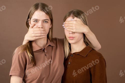 Preview: One of twins covering mouth of another girl keeping hand on eyes of her sister