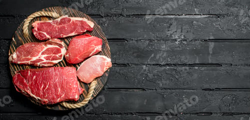 Preview: Raw meat. Beef and pork steaks on a wooden tray.