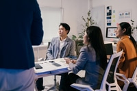 Preview: Asian businesspeople attending a briefing in a modern office, listening to their manager explaining