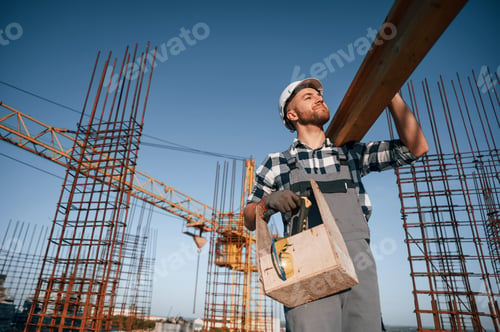 Preview: Moving wooden plank. Man is working on the construction site at daytime