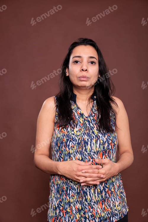 Preview: Indian woman with neutral facial expression, intertwined fingers portrait