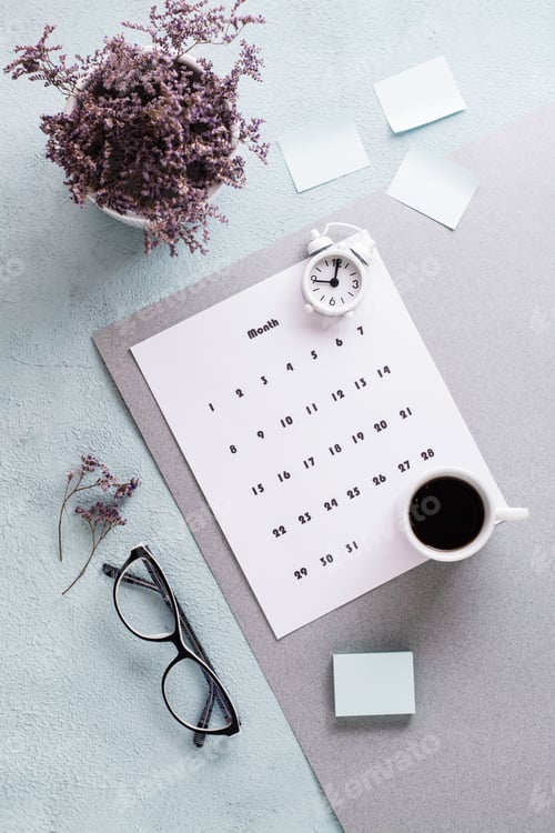 Preview: Blank sheet of monthly calendar, glasses, coffee cup and alarm clock on the desktop.