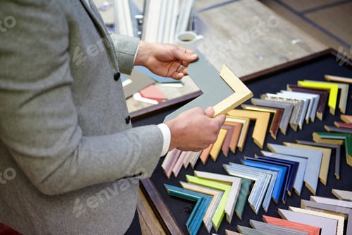 Preview: Cropped shot of framer selecting frame in picture framers workshop