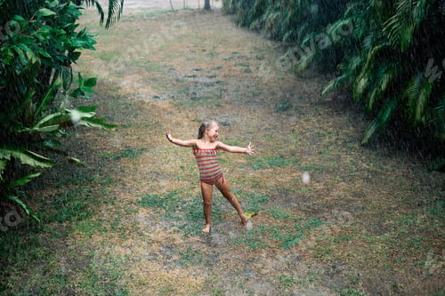Preview: Pretty little girl enjoy the rain and dancing on the street under rainfall in summer