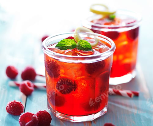 Preview: back lit glasses of raspberry juice cocktail with mint and lemon