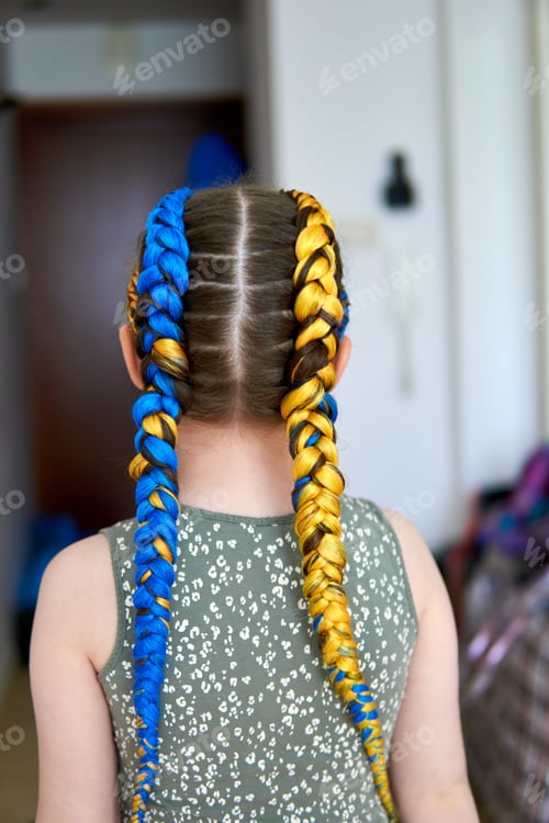 Preview: Young girl showing her support for Ukraine by wearing Dutch braids in the Ukrainian flag colors