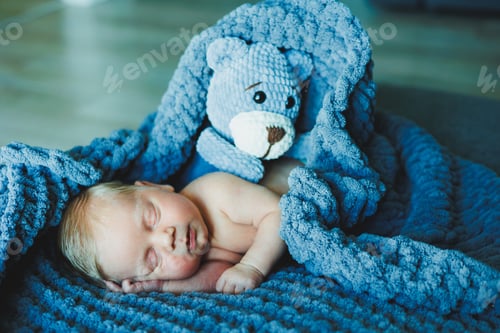Preview: A newborn baby sleeps with a knitted teddy bear. Children's knitted toys. Baby sleep